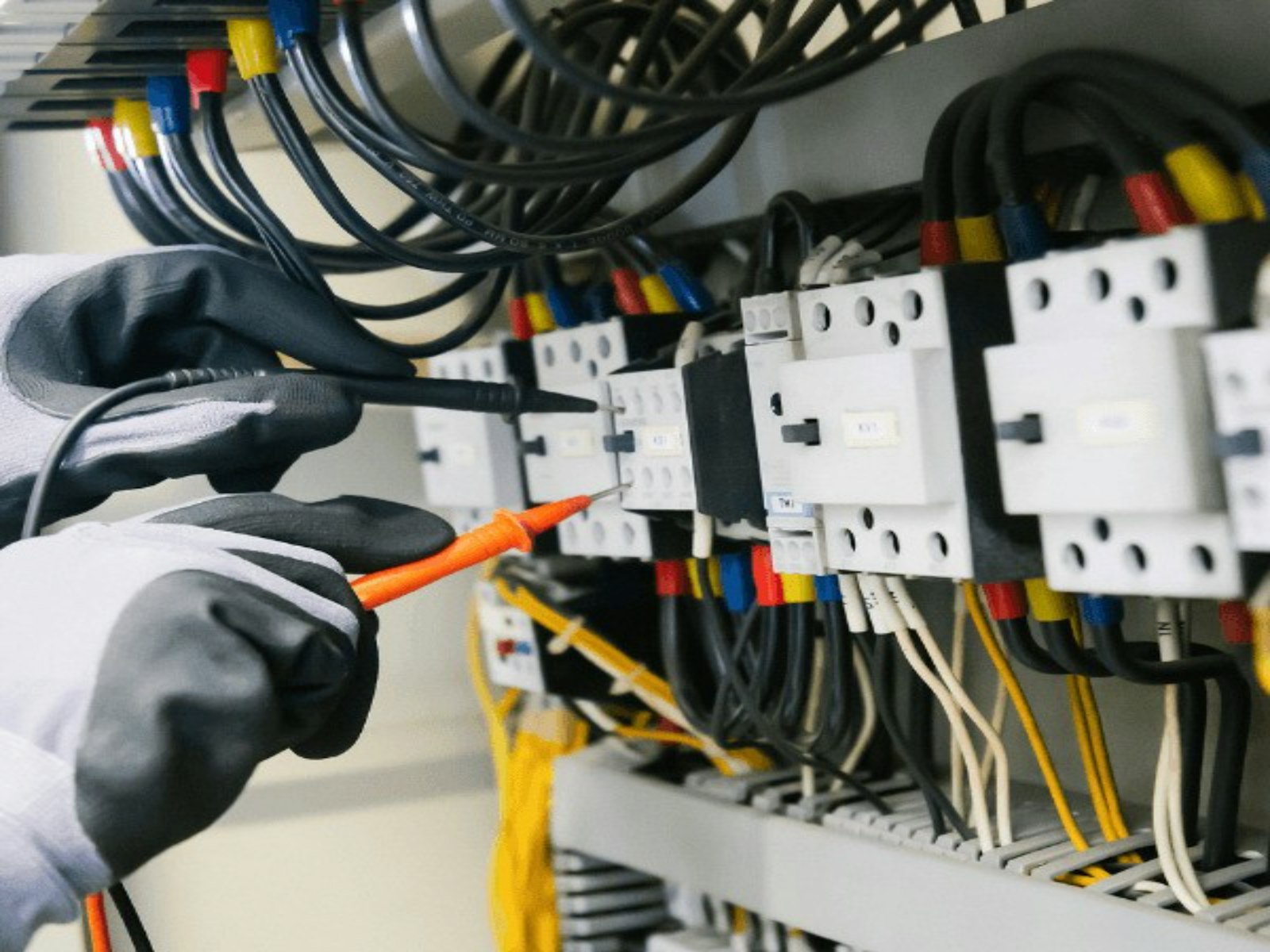 Electrician testing a live electrical control panel with real wiring and breakers